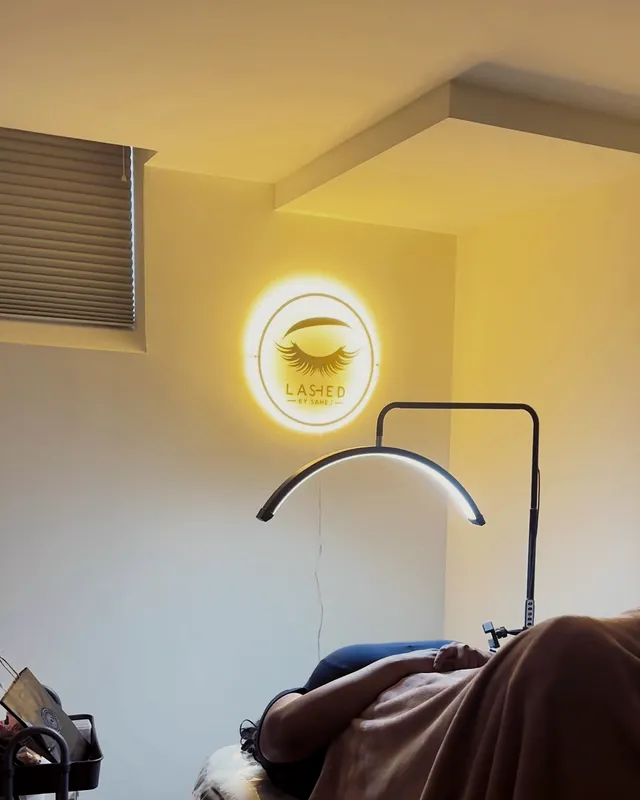 A client relaxing in Sahej’s home lash studio under the lit Lashed sign